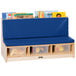 A Jonti-Craft wood literacy bench with blue padded seating and clear plastic bins filled with books.