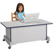 A young girl sitting at a Rainbow Accents navy laminate computer desk with a laptop.