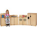 A little girl standing in front of a wooden kitchen set.