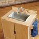 A Jonti-Craft wooden play kitchen sink with a towel hanging from it.