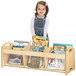 A young girl standing next to a Jonti-Craft wooden book browser with books.