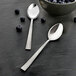 An Amefa stainless steel dessert spoon and a bowl of blueberries on a black surface.