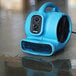 A blue XPOWER air blower on the floor.