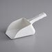 An Avantco Ice white plastic scoop on a gray surface.