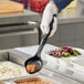 A person in gloves using a black Vollrath Spoodle to serve beans.