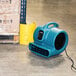 A blue XPOWER air blower on the floor.