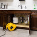 A yellow XPOWER air mover drying carpet in a room with a sink.