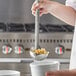 A person using a Vollrath stainless steel ladle to serve food.