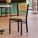 A Lancaster Table & Seating side chair with a light brown vinyl seat and natural wood back in a restaurant