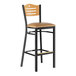 A Lancaster Table & Seating black restaurant bar stool with a natural wood back and light brown cushion.