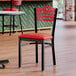 A Lancaster Table & Seating black chair with a red vinyl seat.