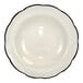 A deep rim stoneware soup bowl in ivory with a scalloped edge and a black rim.
