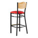 A Lancaster Table and Seating black bar stool with a natural wood back and red vinyl seat.