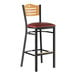 A Lancaster Table & Seating black bar stool with a natural wood back and red vinyl seat.