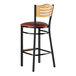 A Lancaster Table & Seating black bar stool with a natural wood back and red cushion.