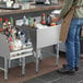 A man standing at a Regency underbar ice bin with bottle holders full of liquid.