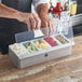 A person using an American Metalcraft stainless steel condiment bar to hold fruit.