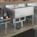 A Regency stainless steel underbar sink with three bowls and a middle drain.