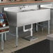 A Regency stainless steel underbar sink with two drainboards.