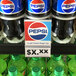 A clear shelf talker holding a label in front of soda bottles on a shelf.