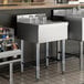 A stainless steel underbar drainboard with four glasses placed upside down on top.