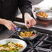 A person cooking potatoes and vegetables in a Choice non-stick fry pan.