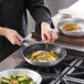 A person using a Choice silicone pan handle sleeve to cook food in a pan.