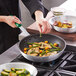 A person using a Choice silicone handle sleeve on a pan.