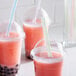 A group of plastic cups with pink drinks and Choice multicolor striped straws.