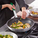 A person using green Choice silicone pan handle covers to cook food in a fry pan.