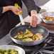 A person using a Choice yellow removable silicone handle sleeve on a pan to cook meat.