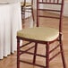 A gold chair cushion with ties placed on a wooden Chiavari chair.