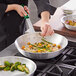 A person using a Choice silicone handle sleeve on a pan to cook food.