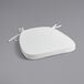 A Lancaster Table & Seating ivory chair cushion with ties on a gray surface.