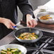 A person cooking brussels sprouts in a Choice aluminum non-stick fry pan.