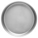 A close-up of a round silver Vollrath pizza pan on a white surface.