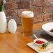 A glass of beer on a table with food.