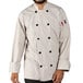 A person wearing a white Uncommon Chef long sleeve chef coat with 10 buttons.