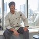 A man in a Uncommon Chef long sleeve chef coat sitting on a window sill.