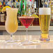 A group of Front of the House Tritan plastic martini glasses on a bar counter.