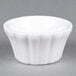 A CAC Bone White China floral ramekin on a gray surface.