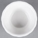 A close-up of a CAC bone white floral ramekin on a gray surface.