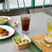 A table with Front of the House hammered plastic highball glasses filled with brown liquid and ice, and a bowl of salad.