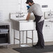 A man in an apron washing a Regency commercial sink.