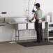 A man washing dishes in a Regency 3 compartment commercial sink in a professional kitchen.