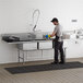 A man washing dishes in a Regency 3 compartment stainless steel sink.