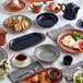 An Acopa Sedona Orange stoneware oblong coupe platter on a table with plates of food.