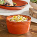 A small orange stoneware ramekin filled with a diced vegetable salad.