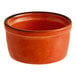 A small, round, orange stoneware ramekin.