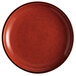 An Acopa Keystone Sedona Orange stoneware coupe plate with black specks.